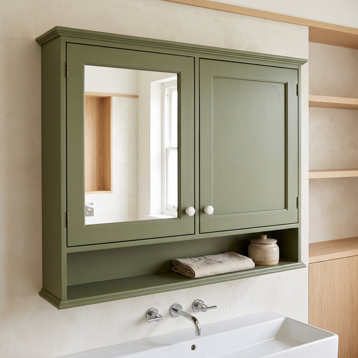 Olivgrüner Spiegelschrank mit Tür und offenem Ablagefach an der Wand in einem hellen Badezimmer