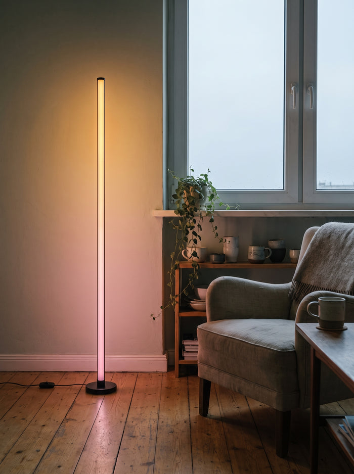 RGB-LED-Stehleuchte 120 cm leuchtet warm in einer Wohnzimmerecke neben einem Sessel
