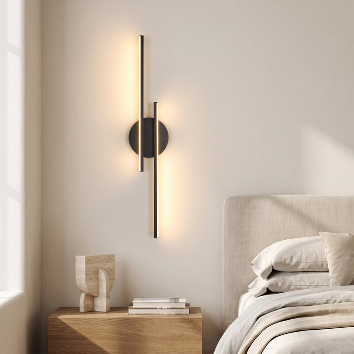 Schwarze LED-Wandleuchte mit zwei versetzten Lichtstaeben in einem hellen Schlafzimmer