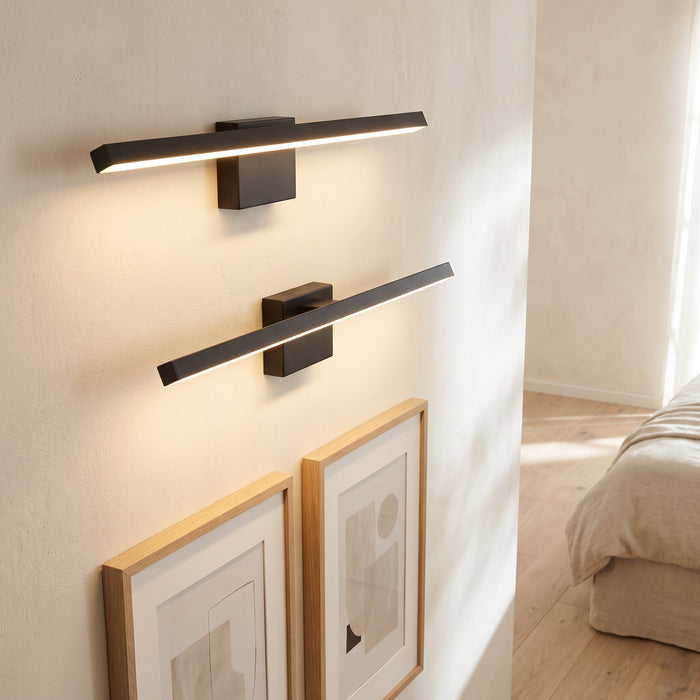 LED-Akku-Wandleuchten im 2er-Set über Bildern in einem hellen Schlafzimmer