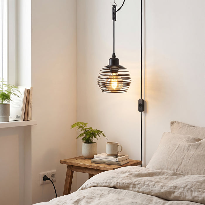Industrial-Pendelleuchte mit Stecker und Schalter über dem Nachttisch im Schlafzimmer