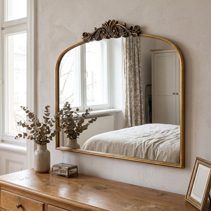 Antiker Bogen-Wandspiegel mit Goldrahmen über einer Holzkommode im Schlafzimmer
