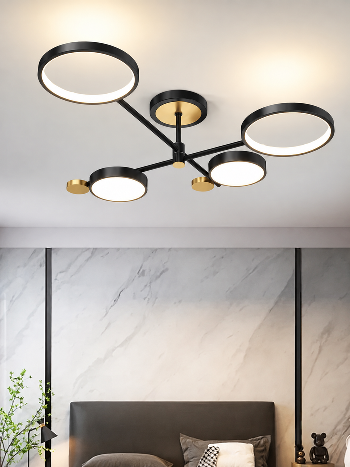 Schwarze vierflammige LED-Deckenleuchte mit zwei Ring- und zwei Scheibenleuchten sowie goldfarbenen Akzenten. KI-Visualisierung der belegten vierflammigen Bauform.