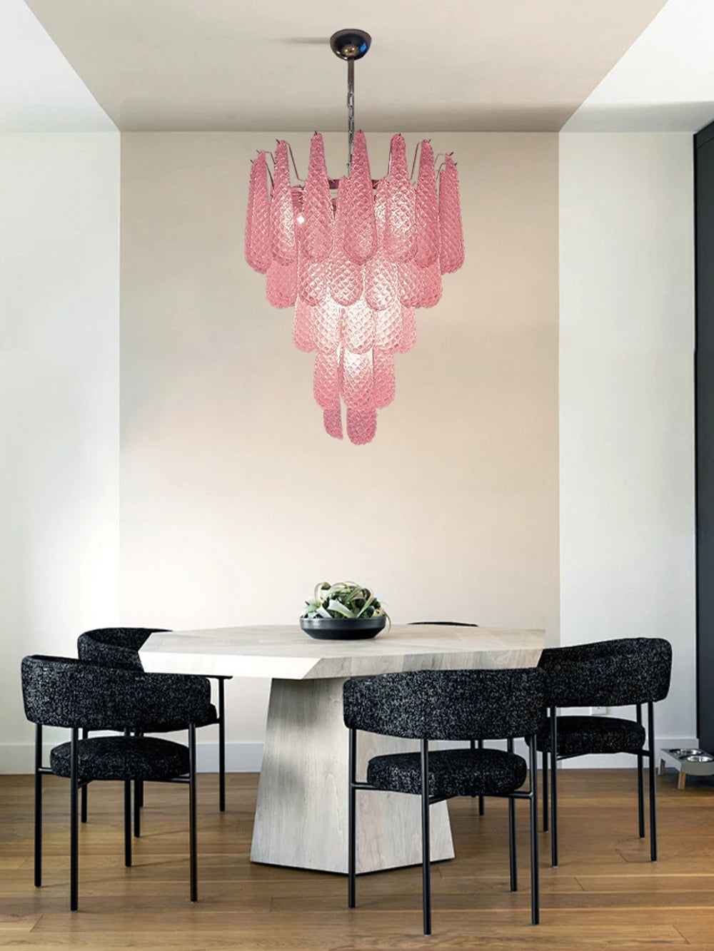 Kronleuchter aus rosa Glas über einem Esstisch mit dunklen Stühlen
