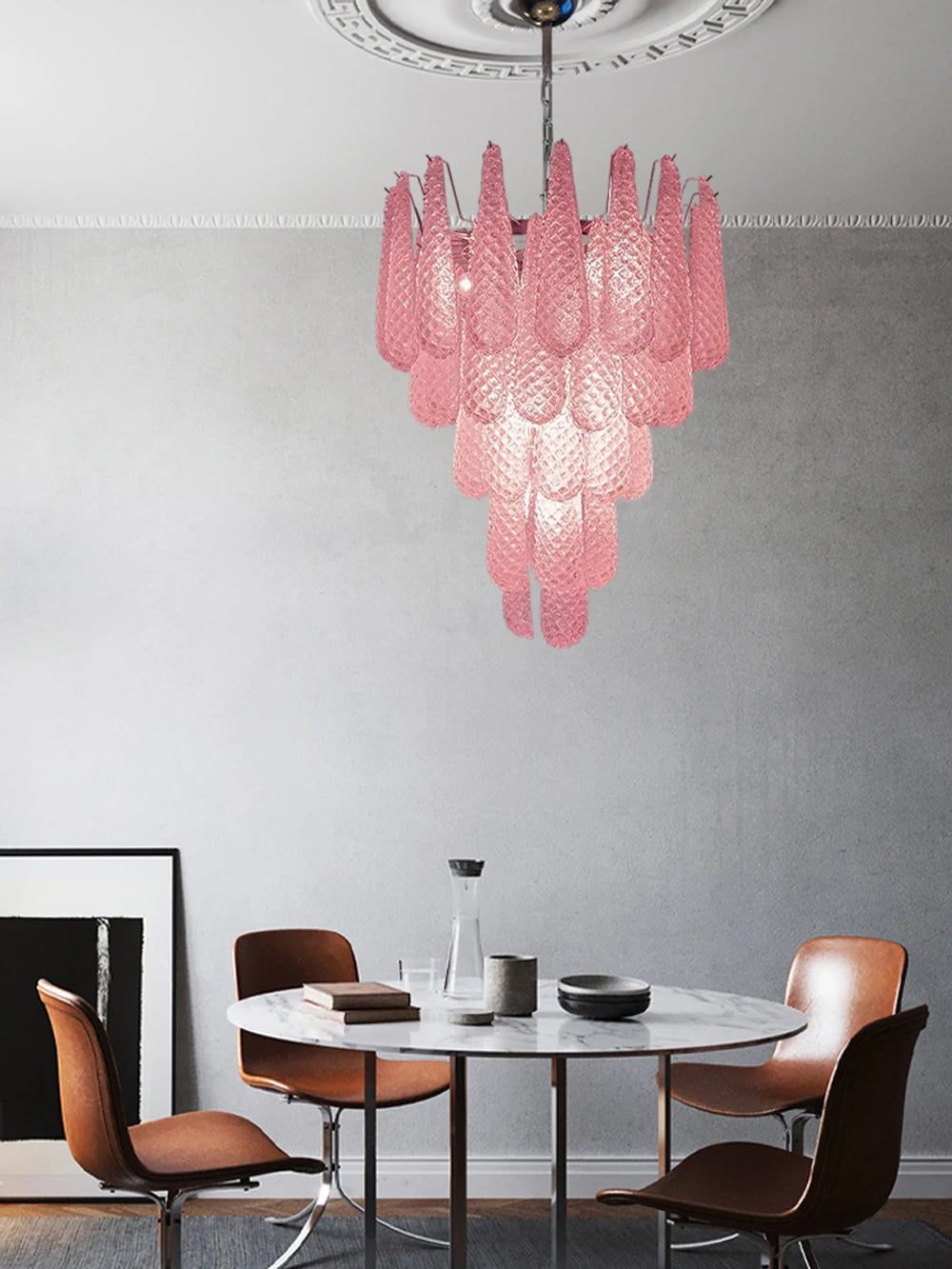 Kronleuchter aus rosa Glas vor grauer Wand über rundem Esstisch