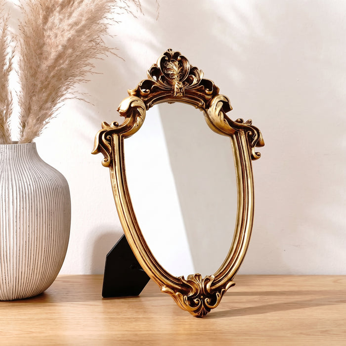 Kleiner ovaler Barock-Dekospiegel in Gold auf einer Konsole in einem hellen Wohnraum
