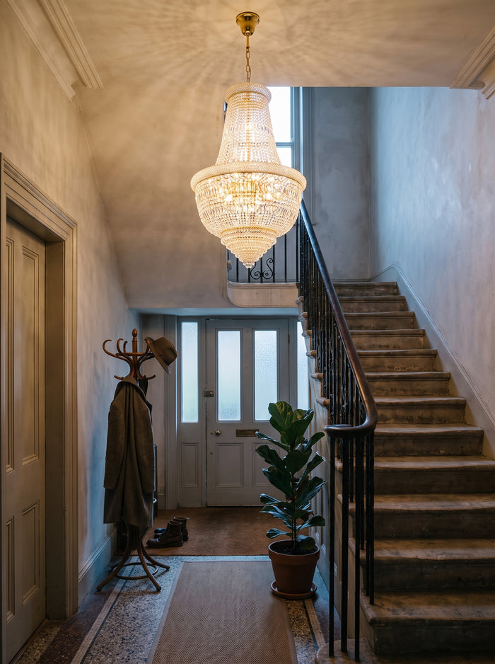 Goldener Kristall-Kronleuchter im Empire-Stil im Treppenhaus eines Altbaus in der Dämmerung
