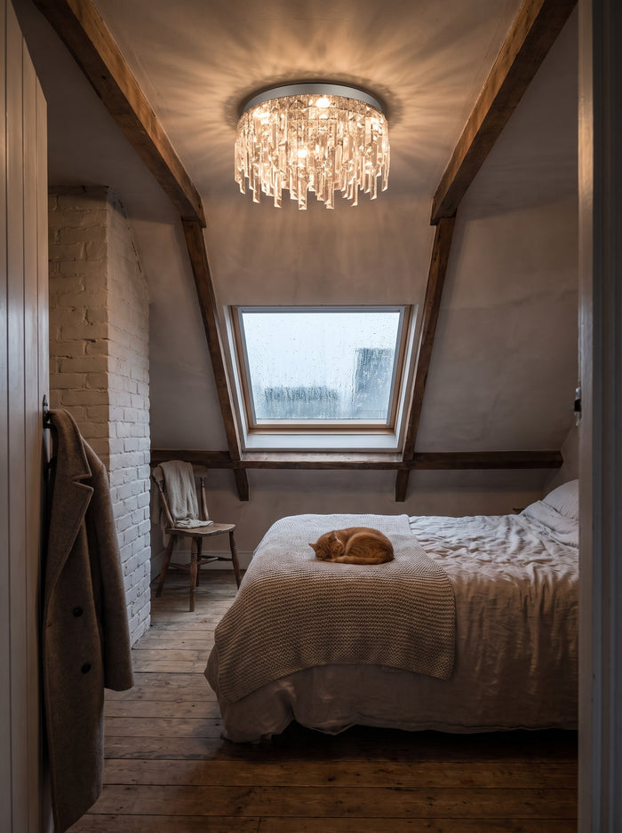 Kristall-Kronleuchter in Silber als Deckenleuchte in einem Dachzimmer mit Holzbalken