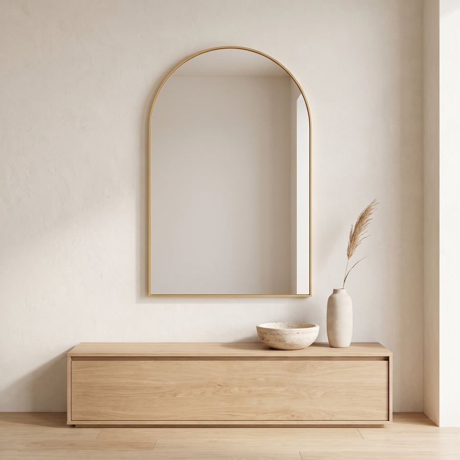 Bogenförmiger Wandspiegel mit schmalem goldenem Aluminiumrahmen in einem hellen Wohnraum