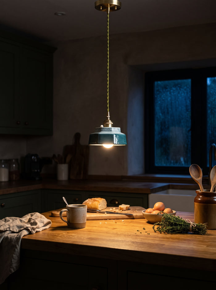 Die blaue Keramik-Pendelleuchte leuchtet abends warm über der Küchenzeile