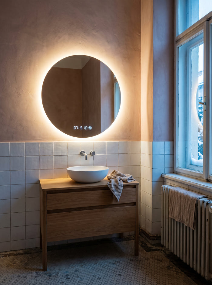 Runder hinterleuchteter LED-Badspiegel mit Uhr über einem Eichen-Waschtisch im Altbau-Bad