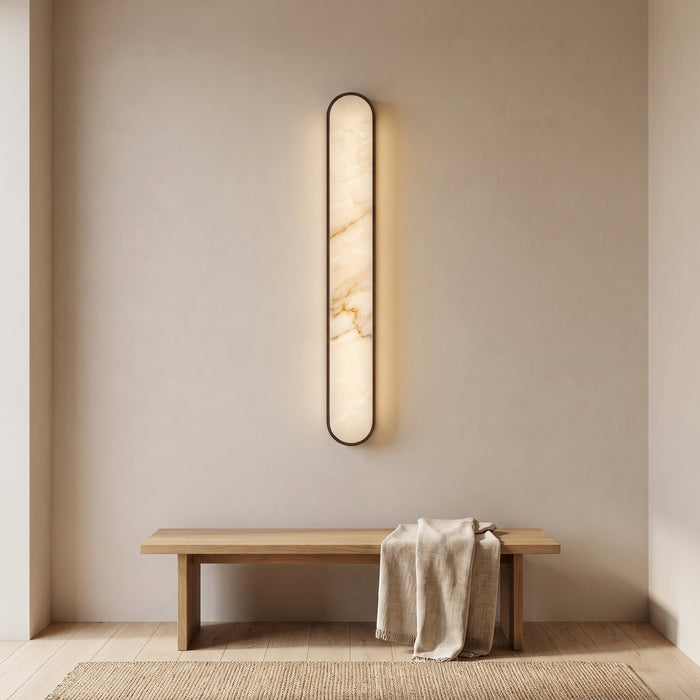 Schlanke ovale Marmor-Wandleuchte mit warmweißem Licht in einem hellen Flur
