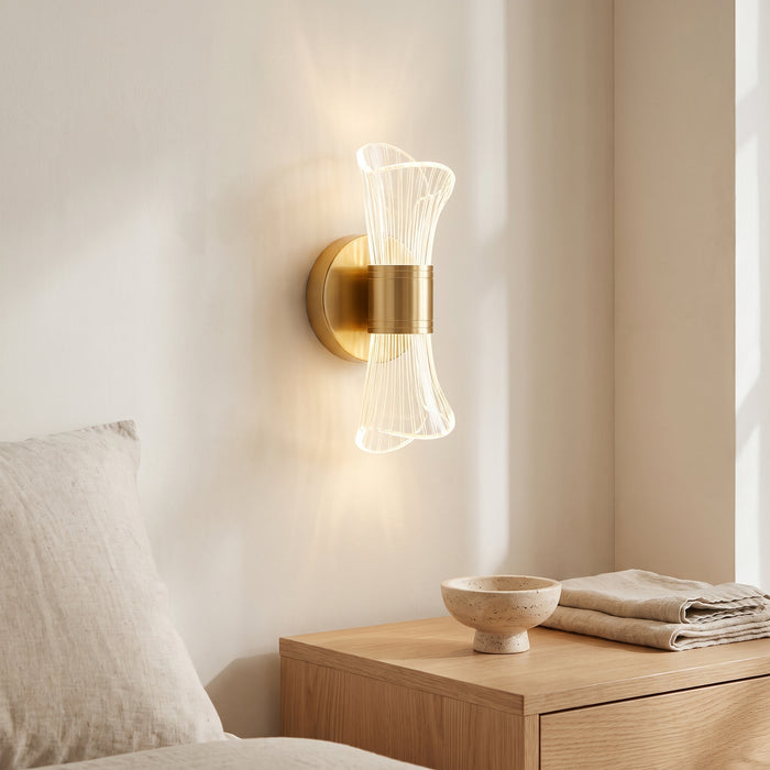 LED-Wandleuchte mit goldener Halterung und klarem Acryl-Diffusor in einem hellen Wohnraum