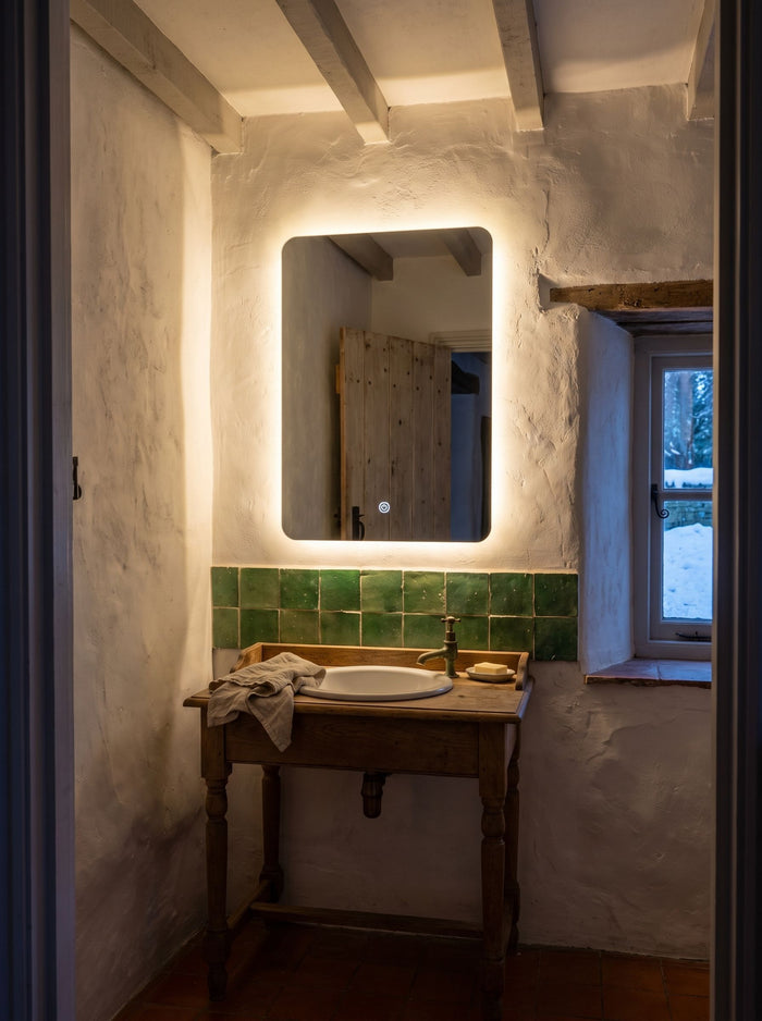 LED-Lichtspiegel 45 × 60 cm über kleinem Waschtisch in einem Gästebad mit Holzbalken und Winterfenster