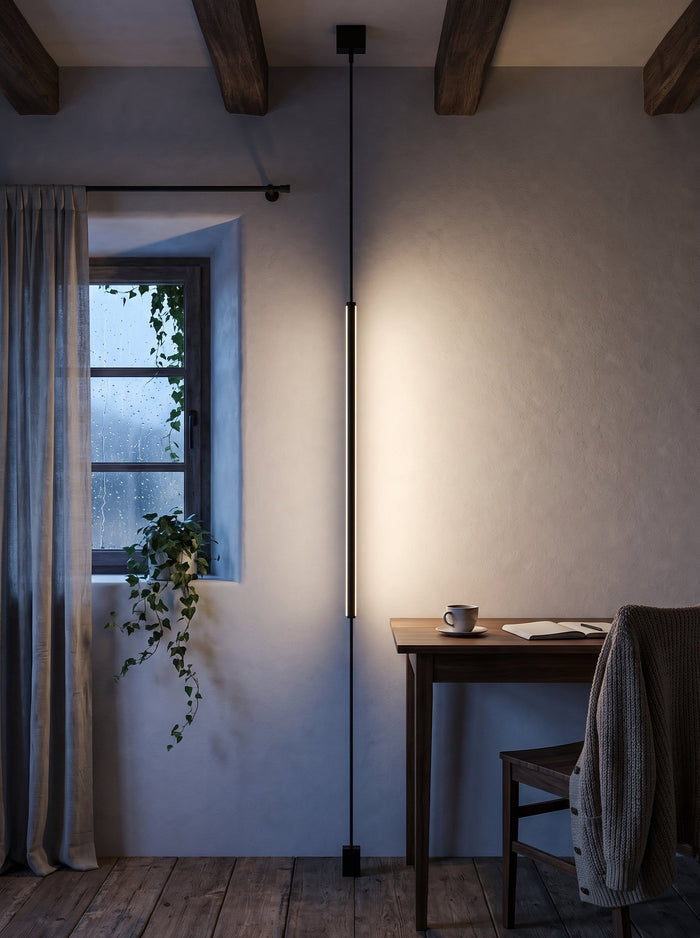 Lineare LED-Spannleuchte in Schwarz, eingeschaltet, in einer Arbeitsecke mit Holzbalken zur blauen Stunde